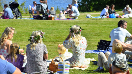 Familien sitzen in einem Park am See