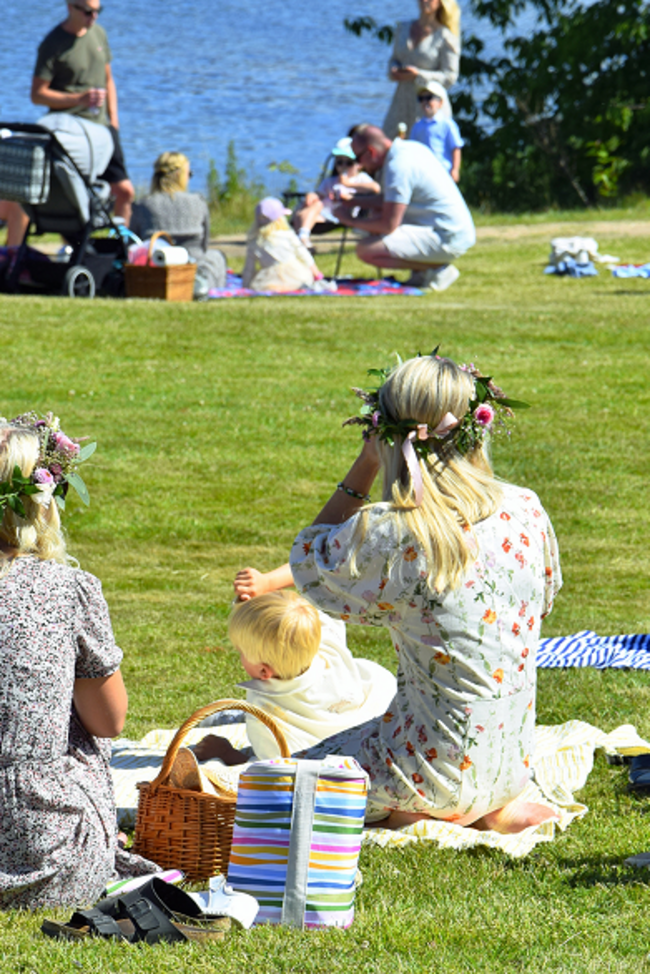 Familien sitzen in einem Park am See