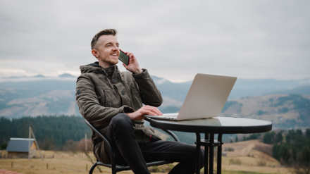 Digitalisierung. Mann mit Laptop und Handy sitz auf Berg und arbeitet